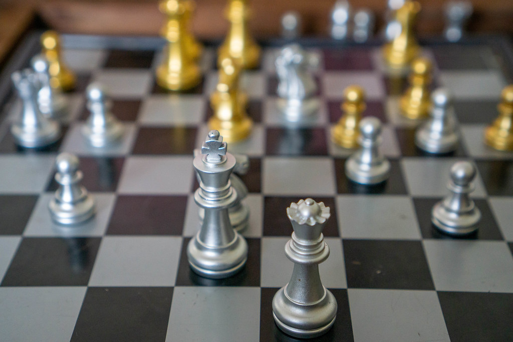 Close Up Photo of ongoing Chess Game on a Portable Magnetic Chess Board with Silver and Golden Chess Pieces