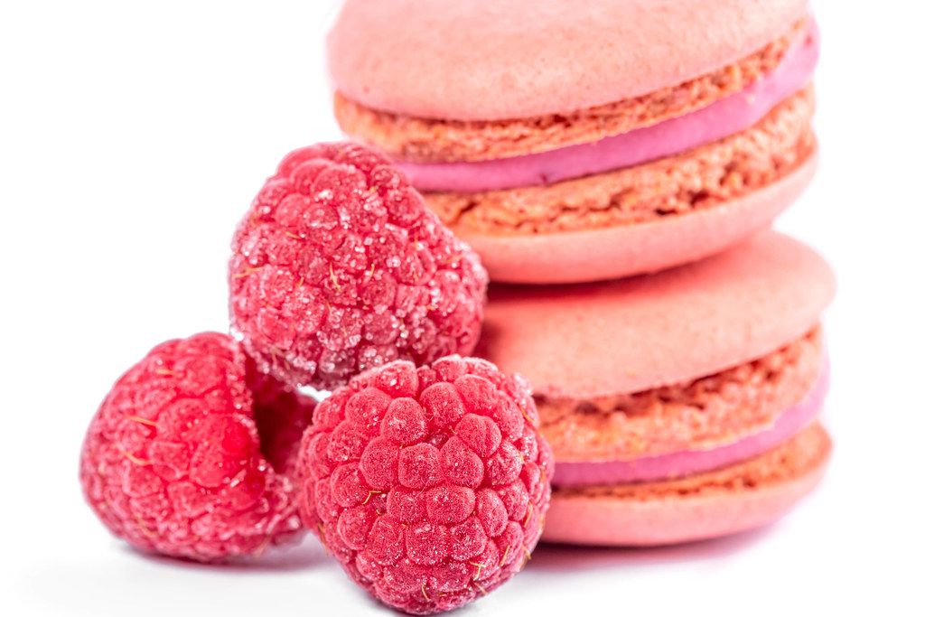 Close-up, pink macaroons with raspberries on white