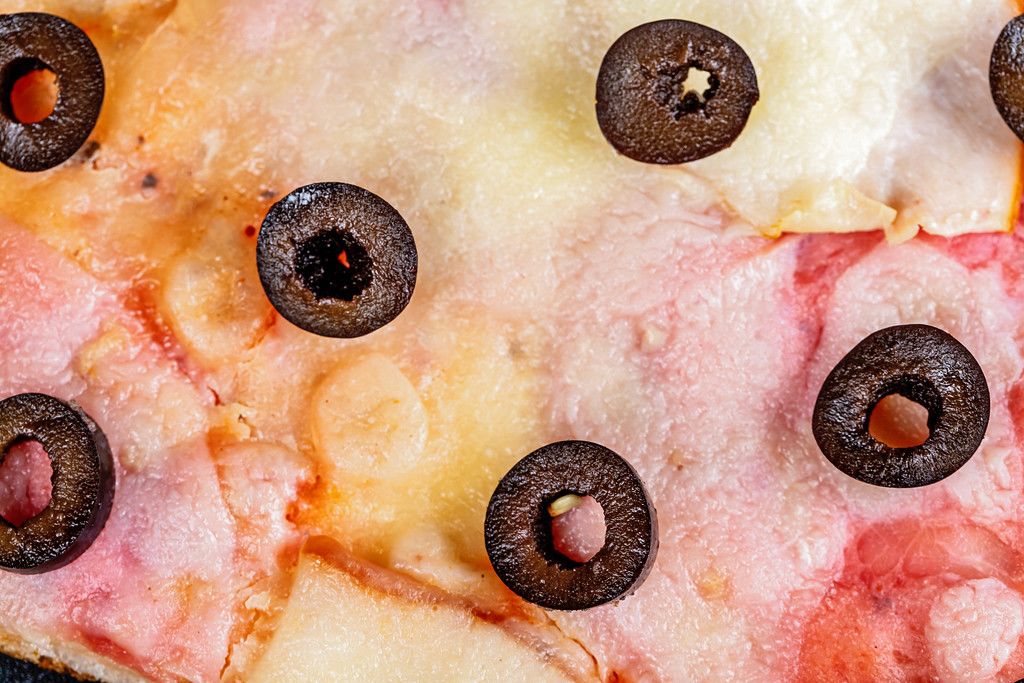Close-up, pizza with ham and slices of black olives