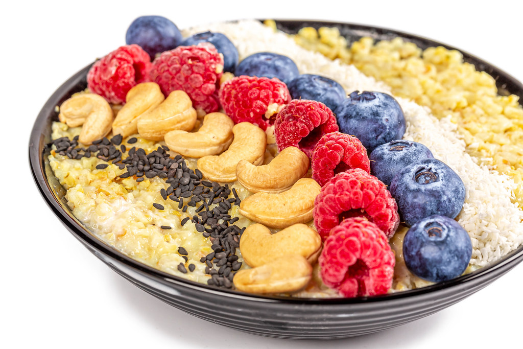 Close-up, porridge with black sesame seeds, cashews, raspberries, blueberries and coconut flakes
