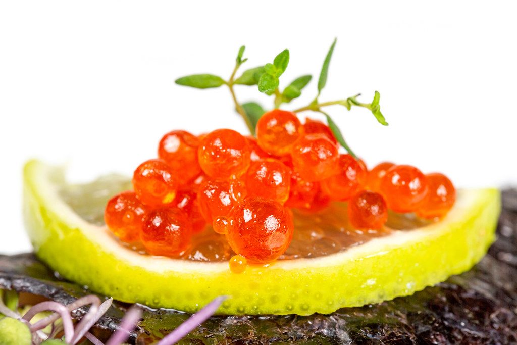 Close-up, red caviar on lime slices with thyme