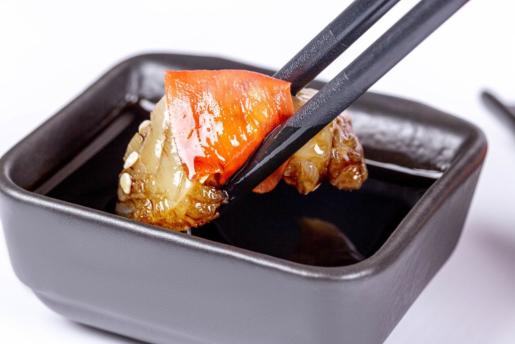 Close-up, sashimi with ginger is dipped in soy sauce