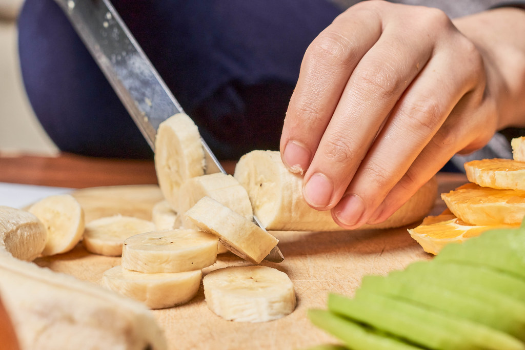 Close-up shot of woman hands slicing banana