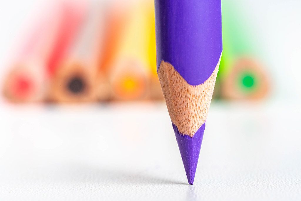 Close-up, tip of purple pencil on blurred background of colored pencils
