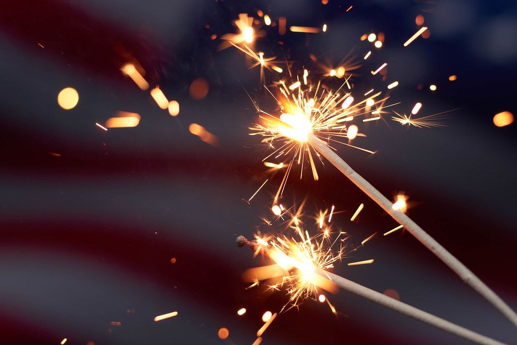 Close-up view of sparklers with American flag in background