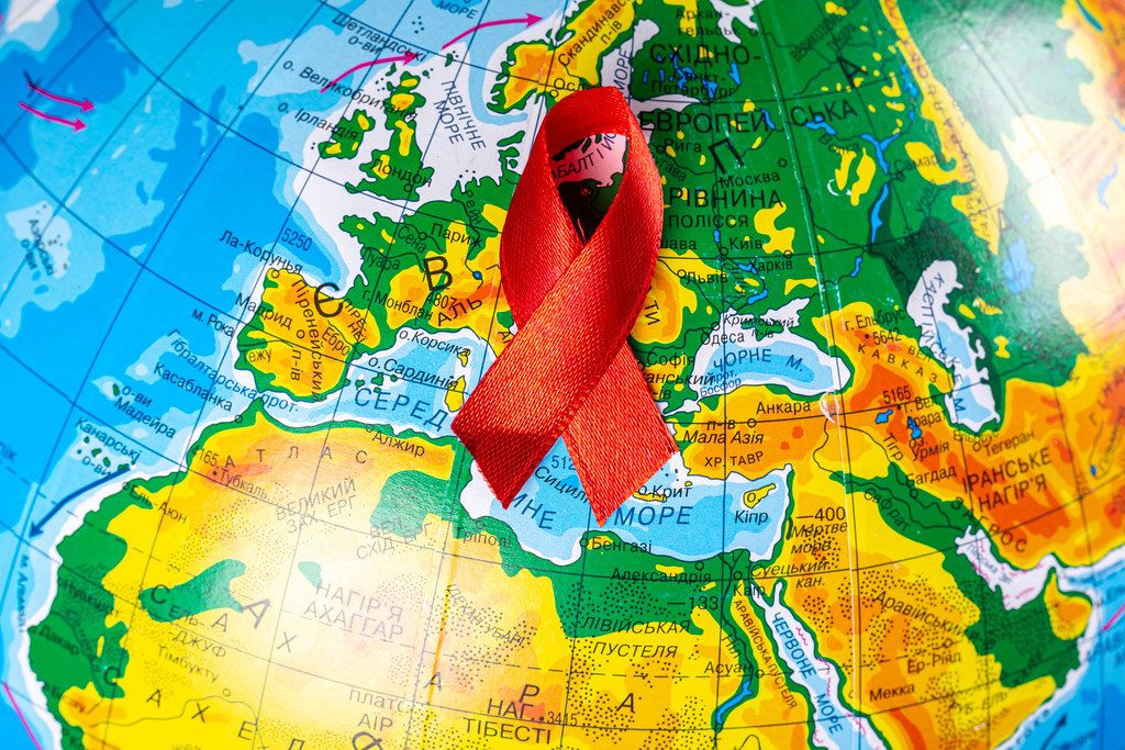 Closeup, world globe with a red ribbon for the fight against AIDS