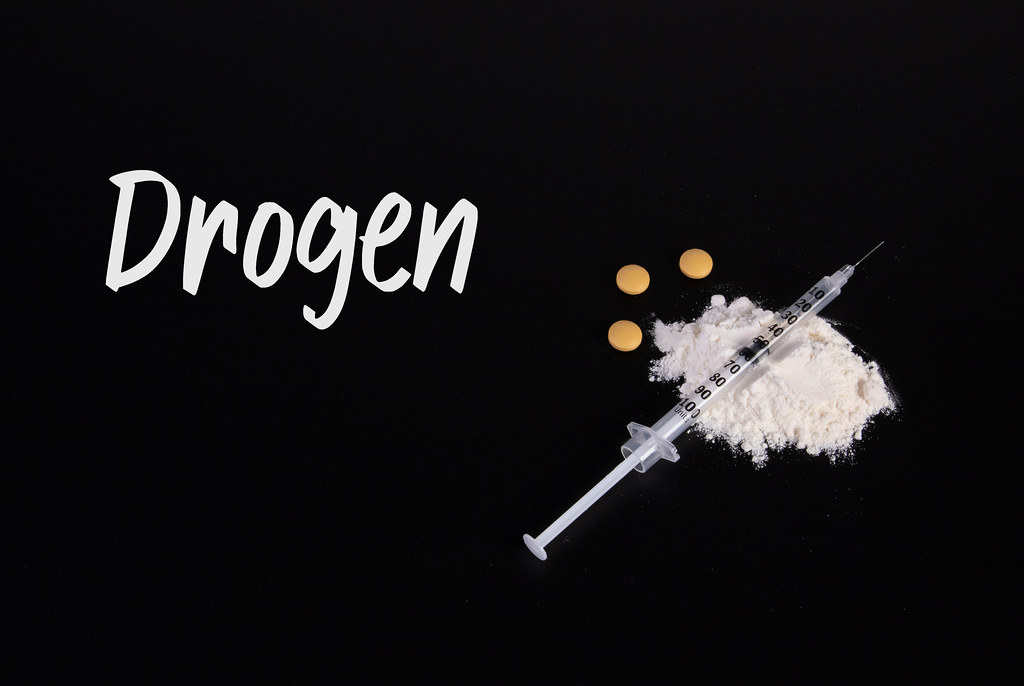 Cocaine powder with syringe and Drogen text on black table