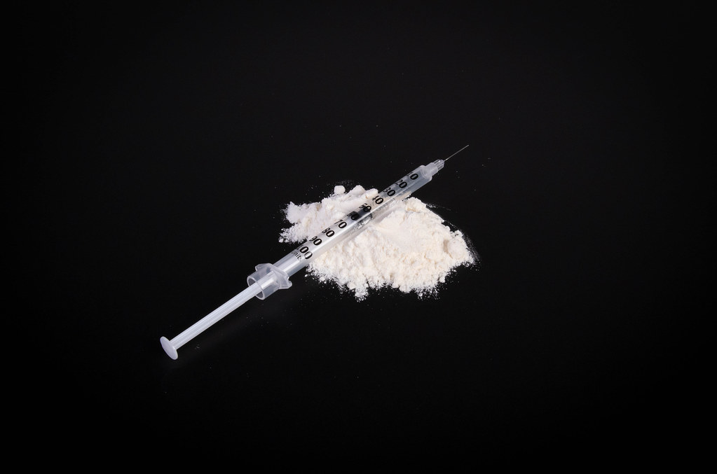 Cocaine powder with syringe on black table