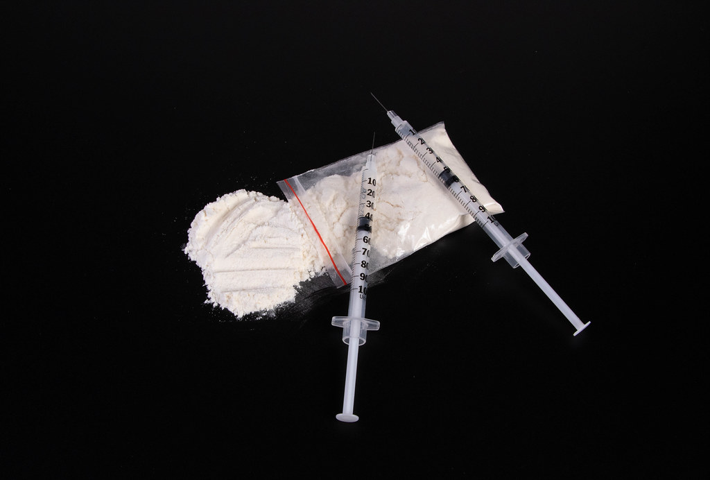 Cocaine powder with syringes on black table