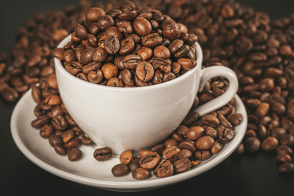 Coffee cup with roasted coffee beans, close up