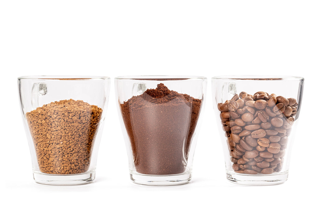 Coffee granules, ground and coffee beans in glass cups on white background