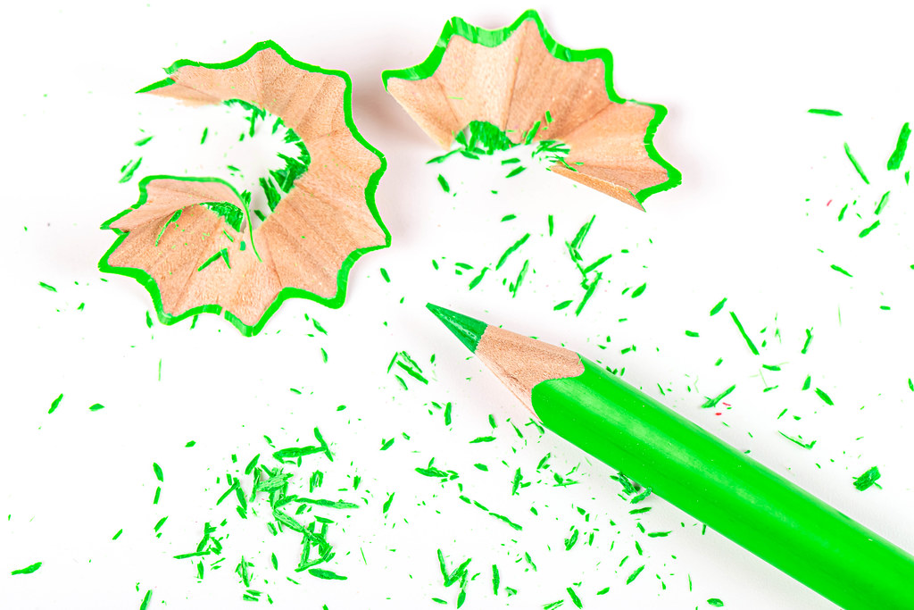 Color green pencils with pencil shavings on white background