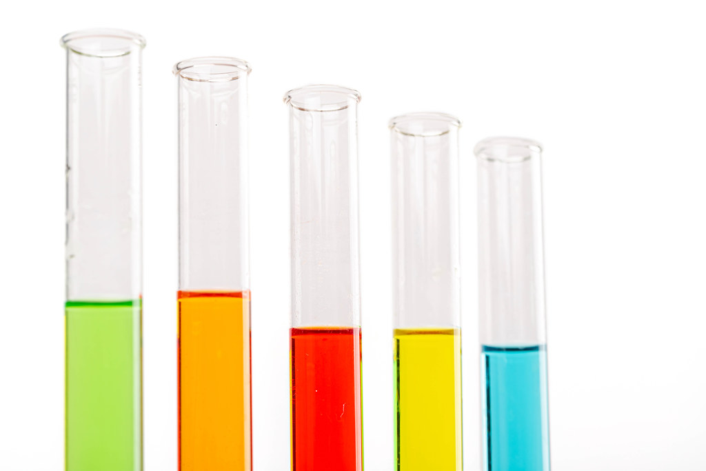 Colored liquids in five test tubes over white background
