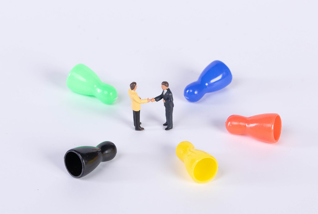 Colorful pawns with two businessman shaking hands