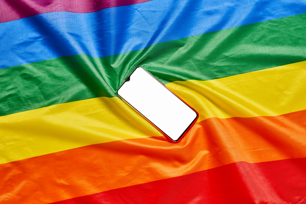 Colorful rainbow flag and mobile phone with blank screen