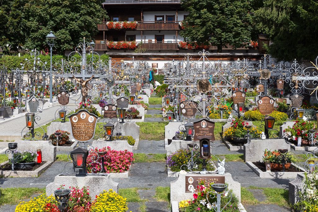 Colourful cemetery with flowers and gravestones with photos of the dead on metal plaques in Alpbach