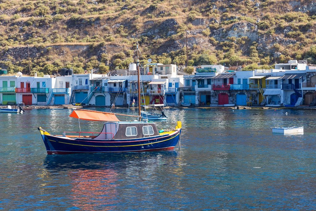 Colours of Greece: blue, yellow and red fishing boat in front of the fisherman
