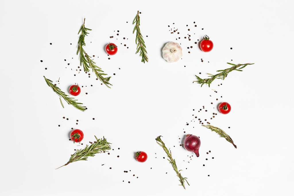 Composition of fresh cherry tomatoes, onion and garlic with herbs on white background