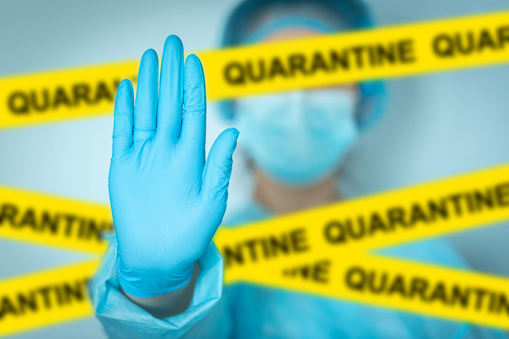 Concept quarantine alert with blurred doctor with mask and protective suit, doctor and isolation with yellow ribbons for quarantine