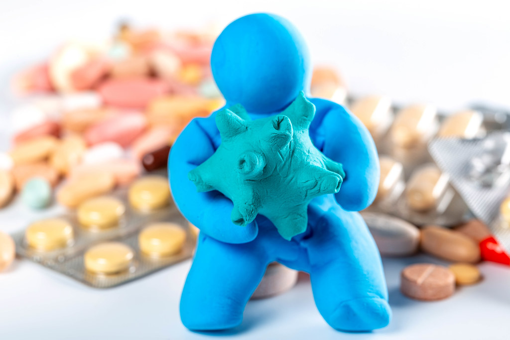 Conceptual background of the danger of coronavirus - a man made of plasticine with a model of a virus in his hands