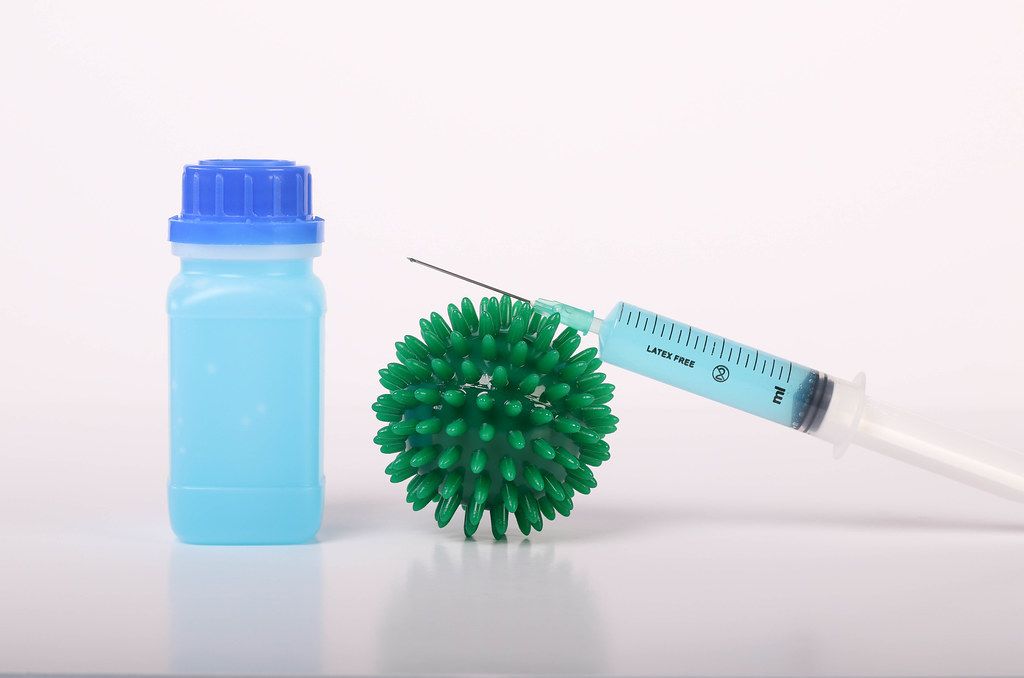 Coronavirus bacteria with syringe and bottle with blue fluid