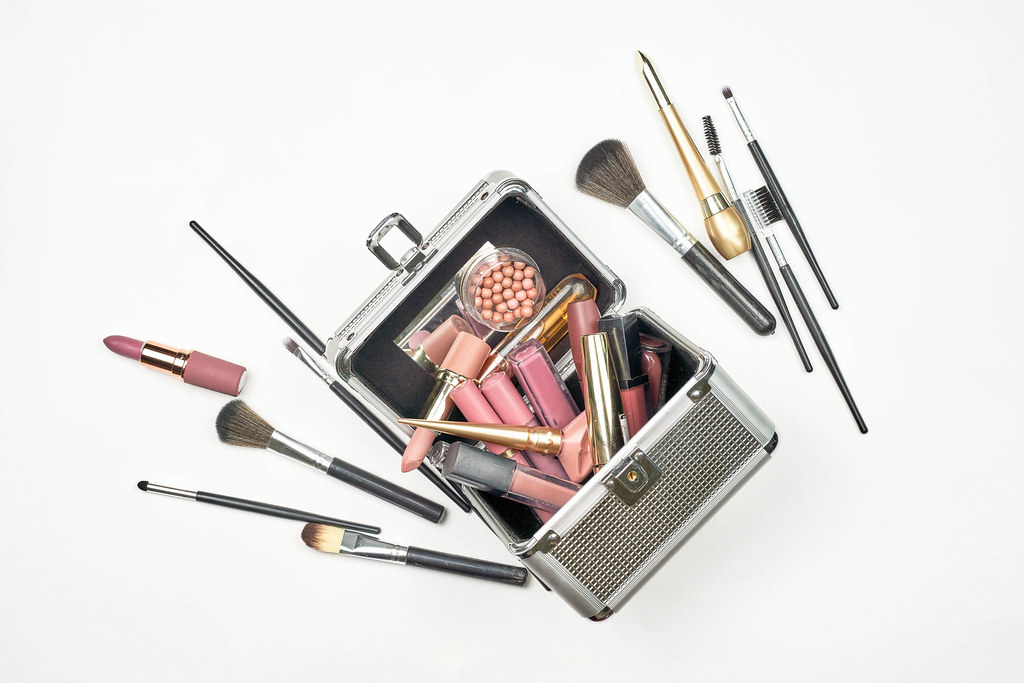 Cosmetic box with professional beauty tools and accessories on white background