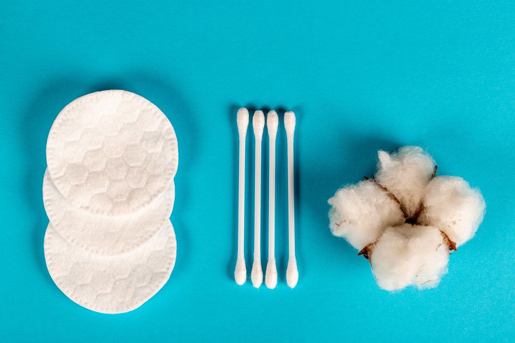Cotton flower, cotton pads and sticks on blue background