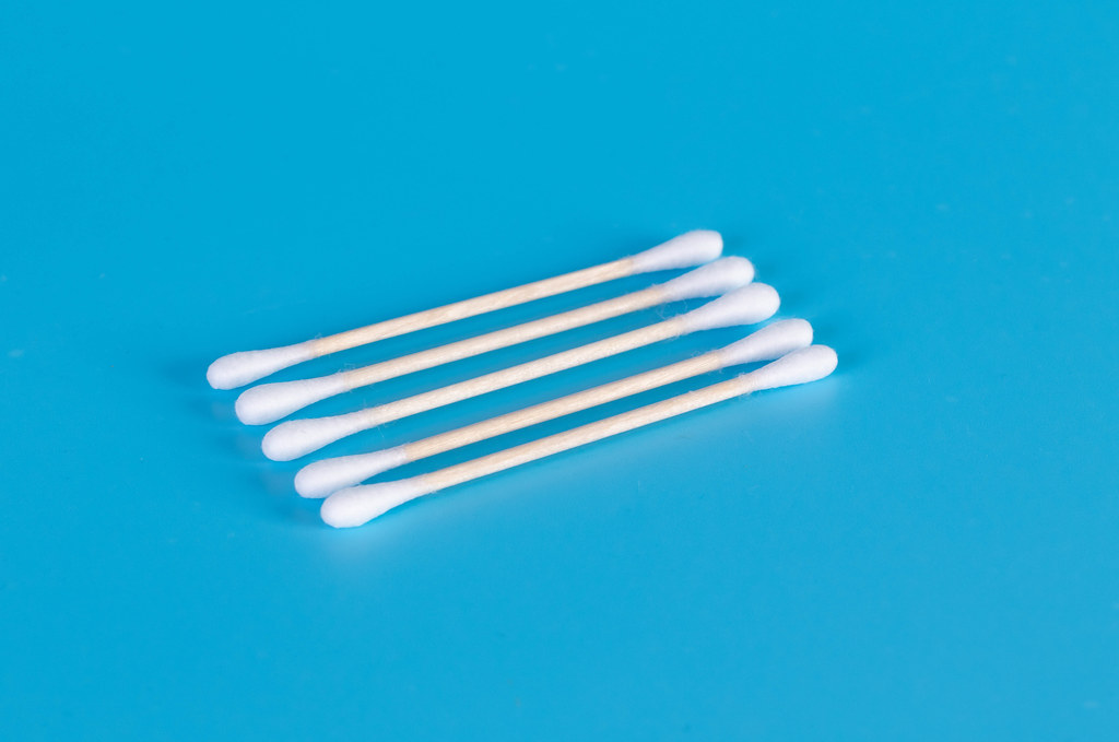 Cotton swabs on a wooden base for the ears on a blue background