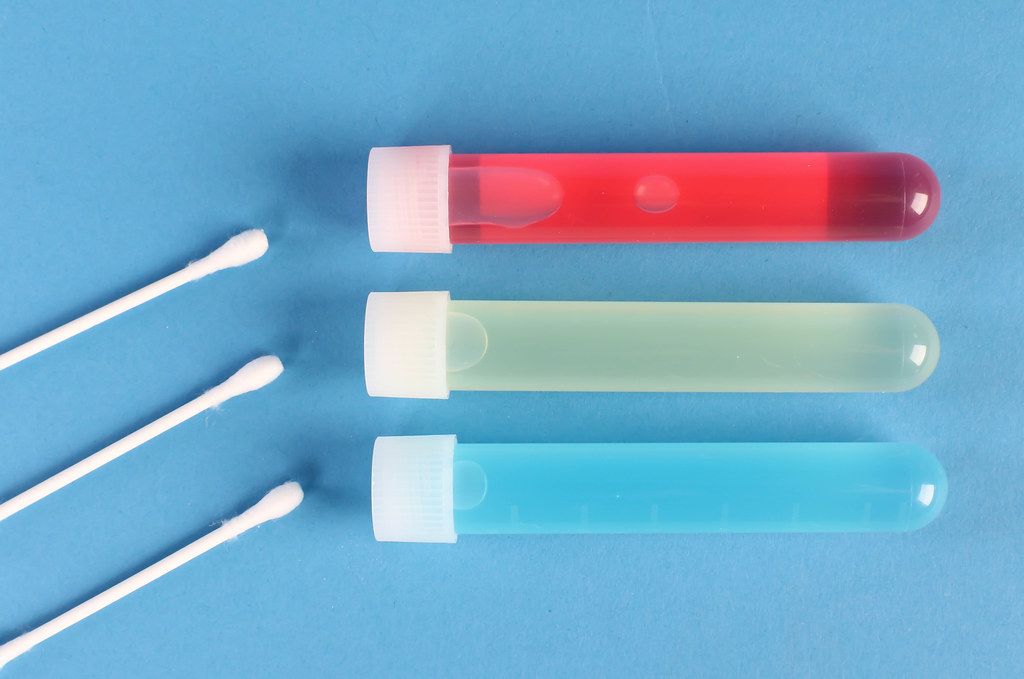 Cotton swabs with test tubes on blue background