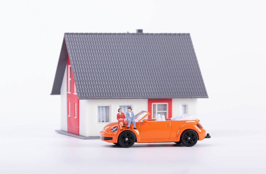 Couple sitting on a car in front of a new house