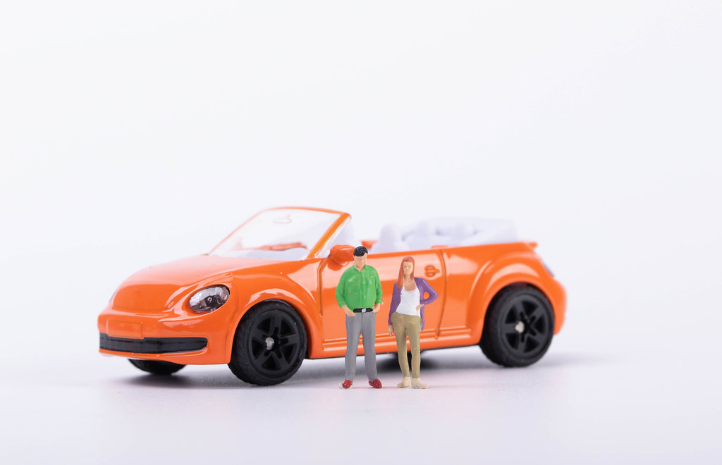 Couple standing in front of orange car