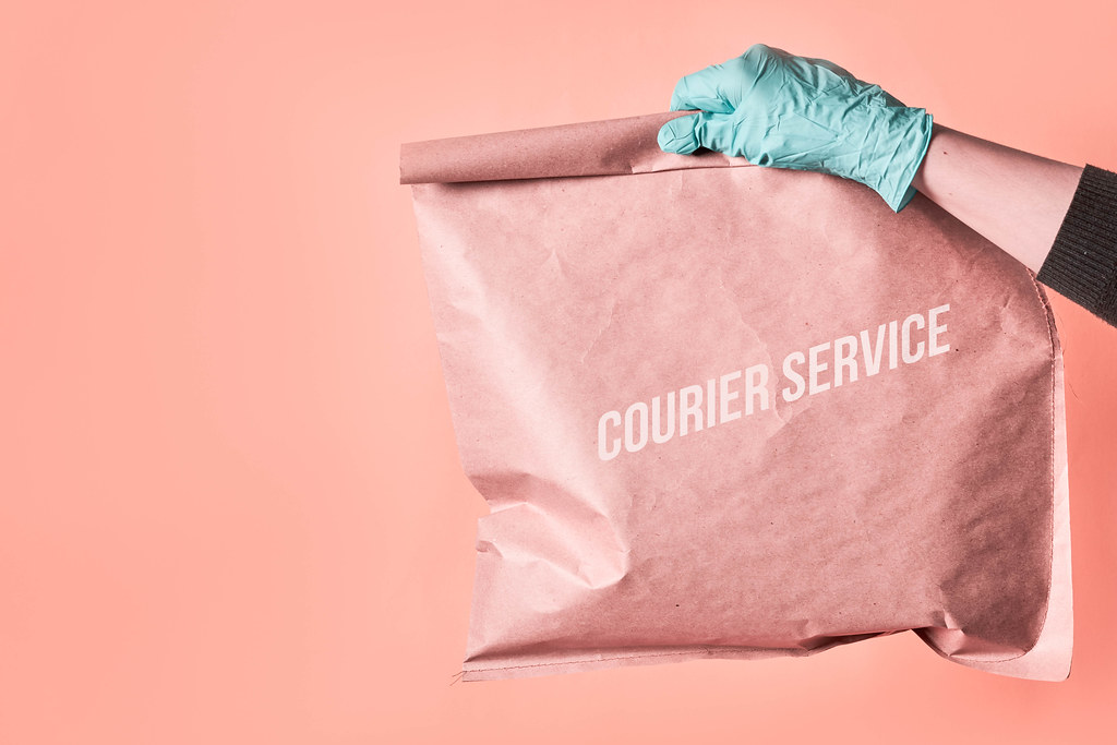 Courier service - deliveryman holding paper bag with products