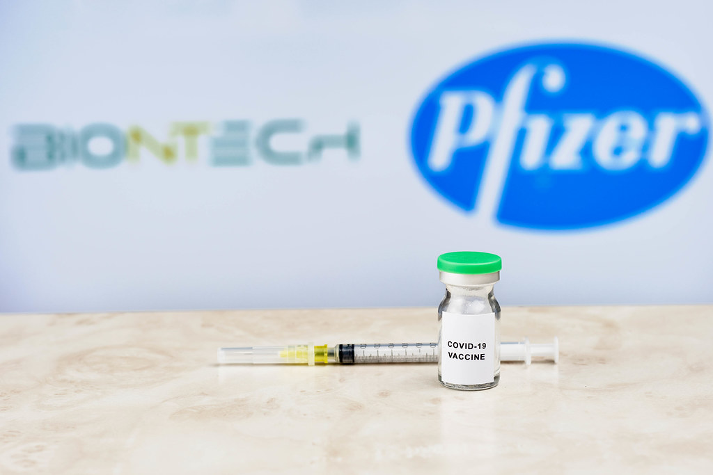 Covid-19 vaccine and syringe against Biontech and Pfizer logos