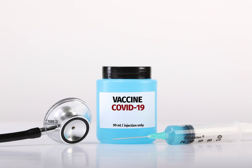 Covid-19 vaccine with stethoscope and syringe on white background