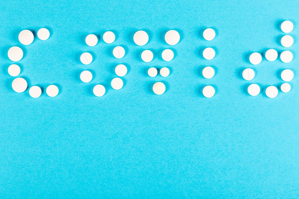 Covid word made from pills on blue background