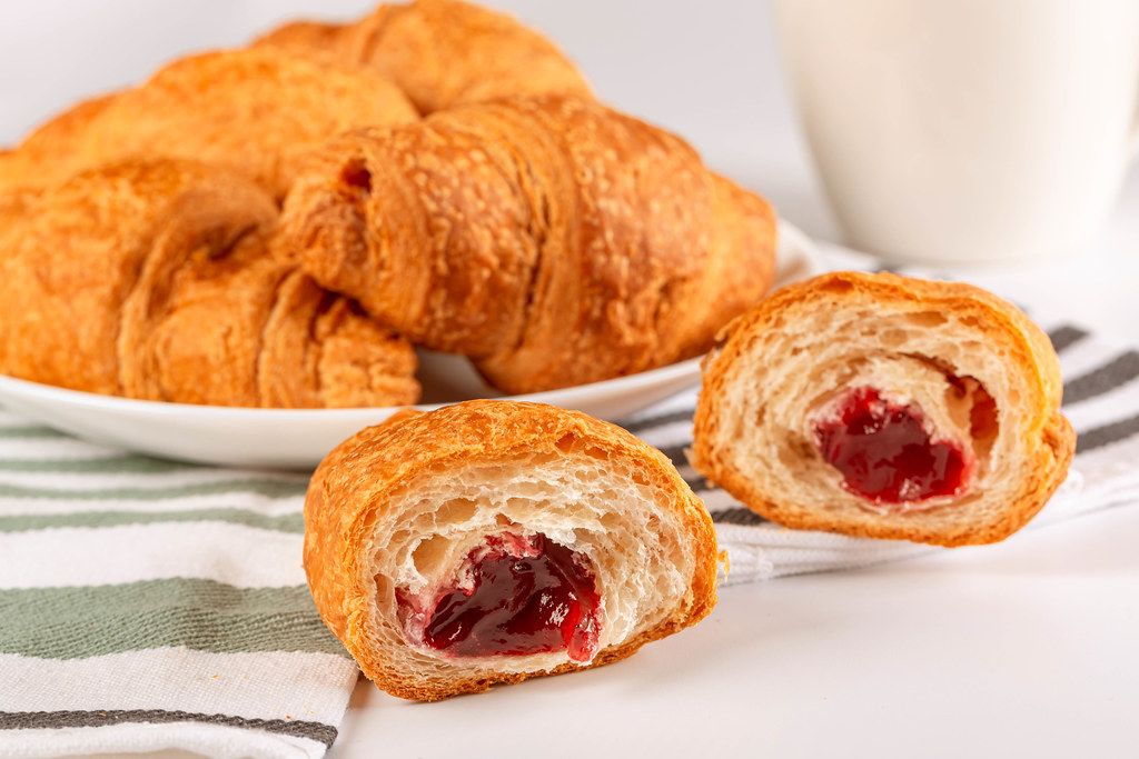 Croissants with fruit jam on the kitchen table
