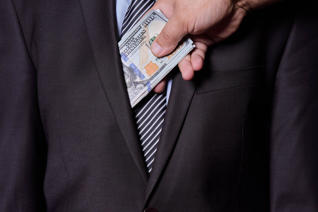 Cropped view of a man putting cash into pocket of business partner