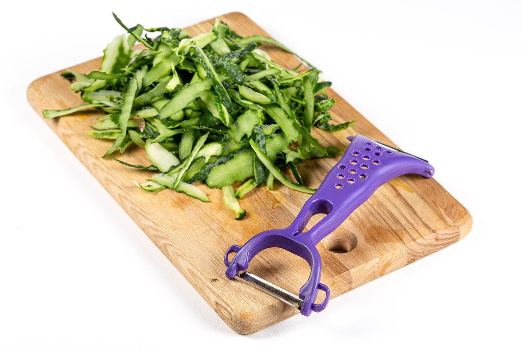 Cucumber skin and knife for cleaning vegetables on kitchen board