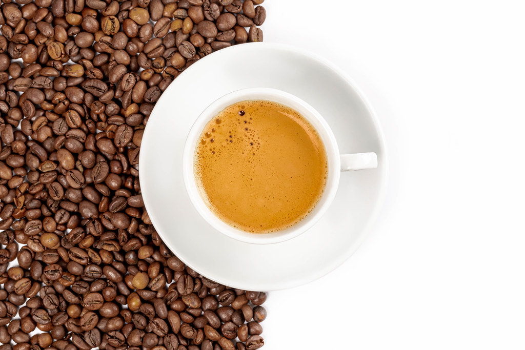 Cup of coffee on a background of beans and on white, top view