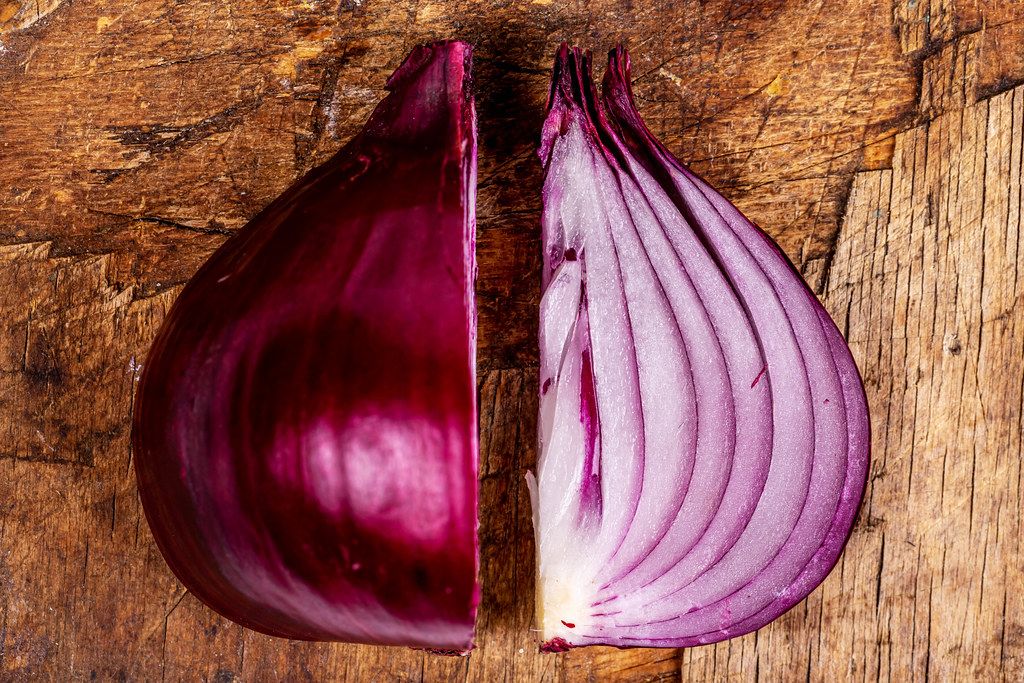 Cut purple onion on an old wooden background, top view