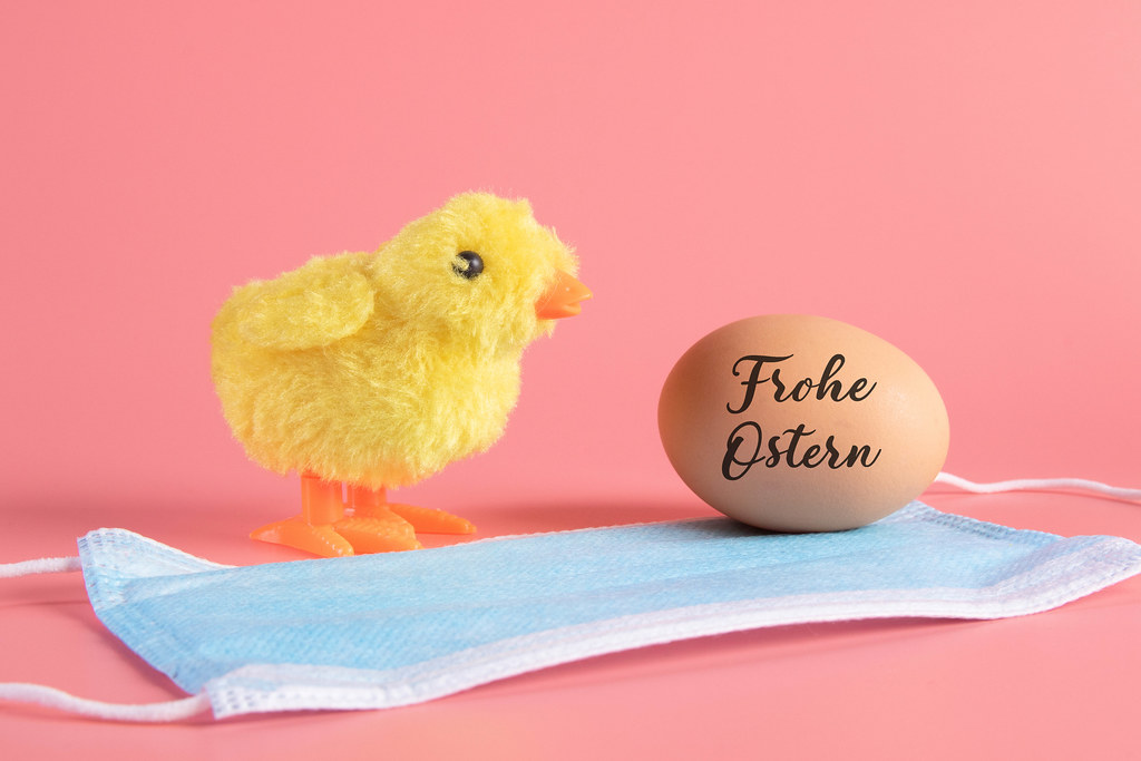 Cute little chicken, medical face mask and egg with Frohe Ostern text