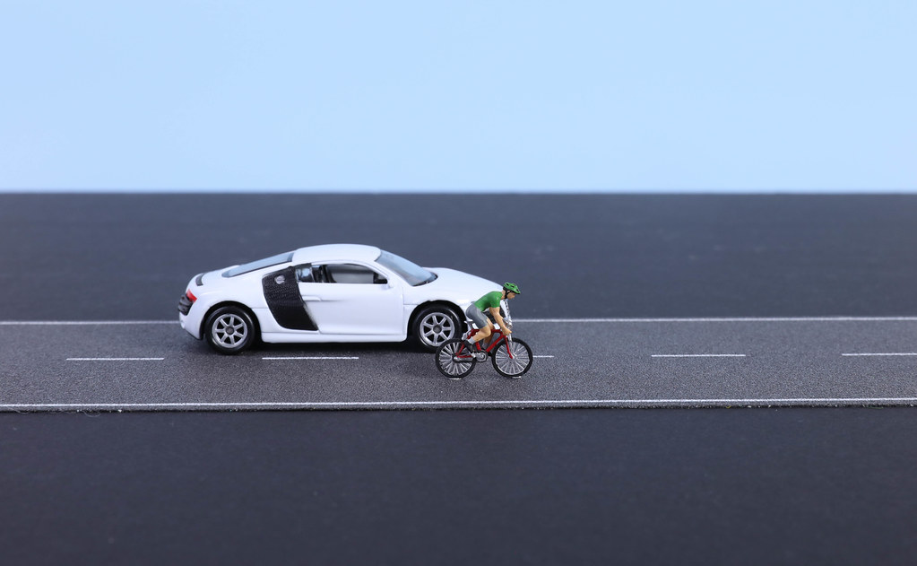 Cyclist and white car on the road