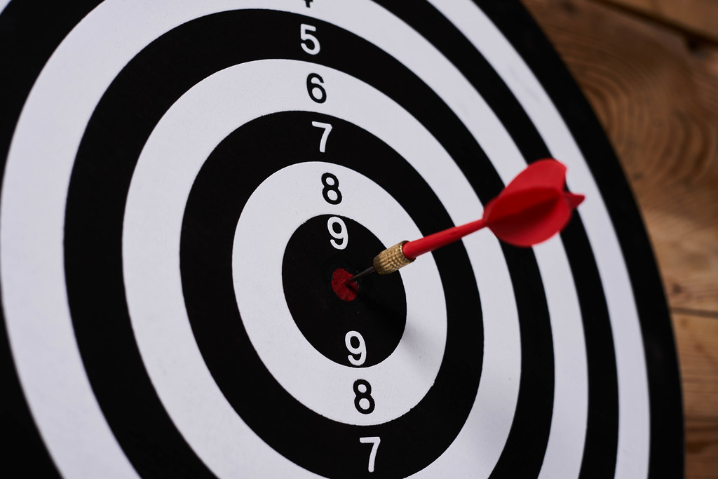 Dart arrow hitting on target center on bullseye in wooden dartboard