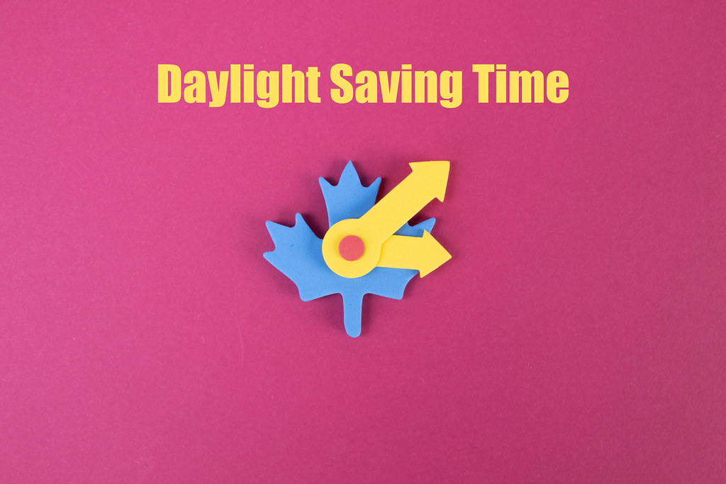 Daylight Saving Time text with clock on pink background