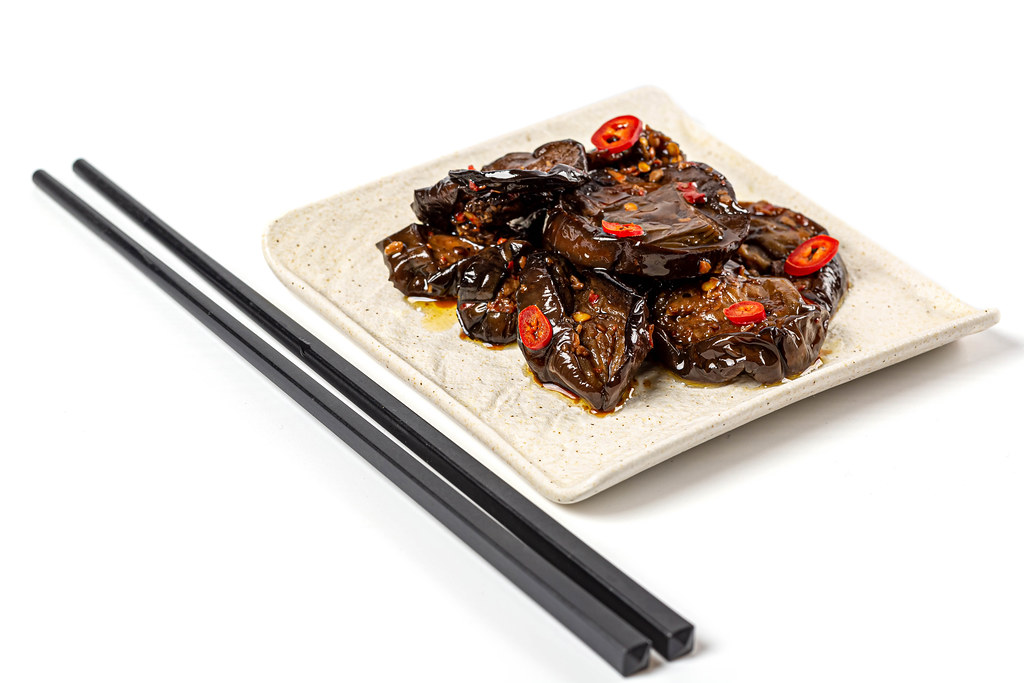 Delicious spicy eggplant with sauce on white with chopsticks