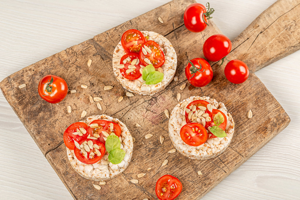 Diet food concept, rice breads with tomato, sunflower seeds and basil, top view