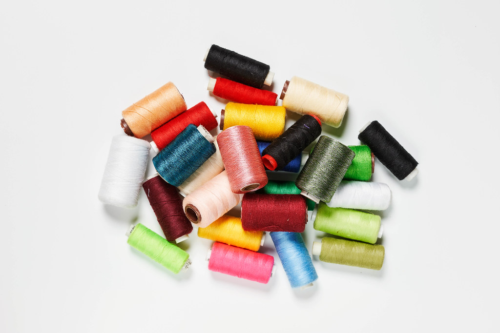 Different colored spools of thread on white background