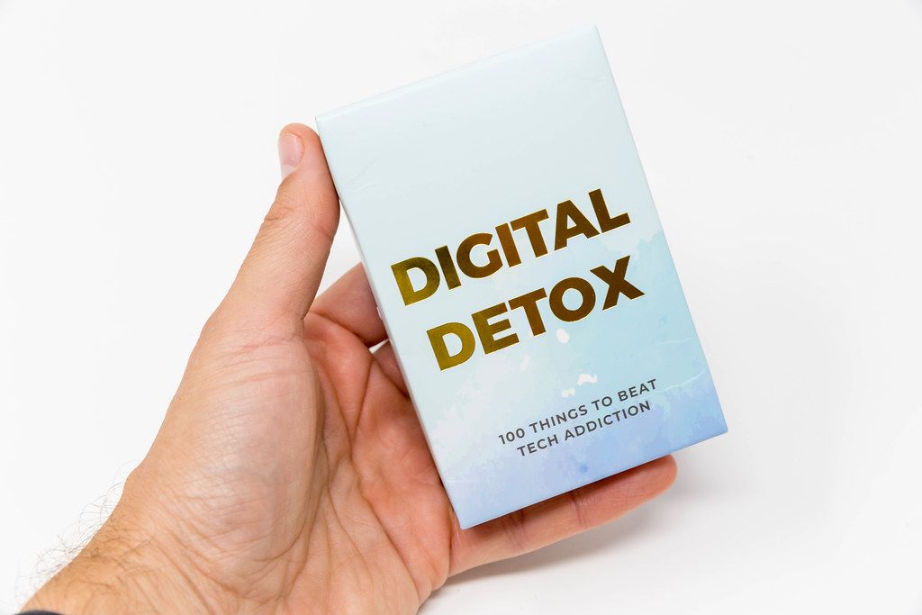 Digital detox: 100 things to beat tech addiction. Hand holds box of cards. Advice to disconnect, go offline