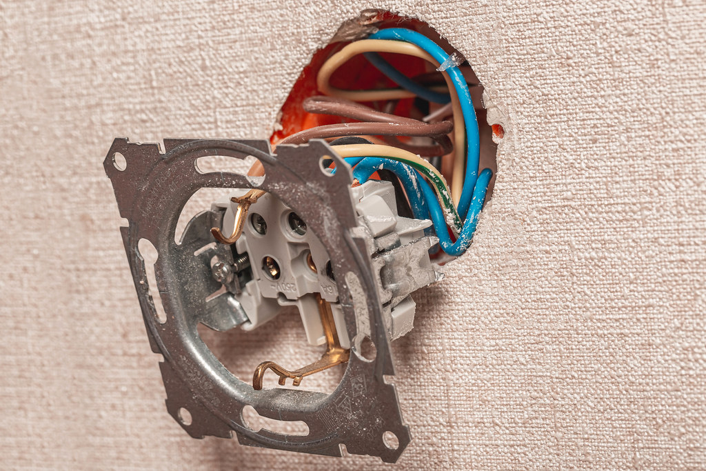 Disassembled socket with wires hanging on the wall