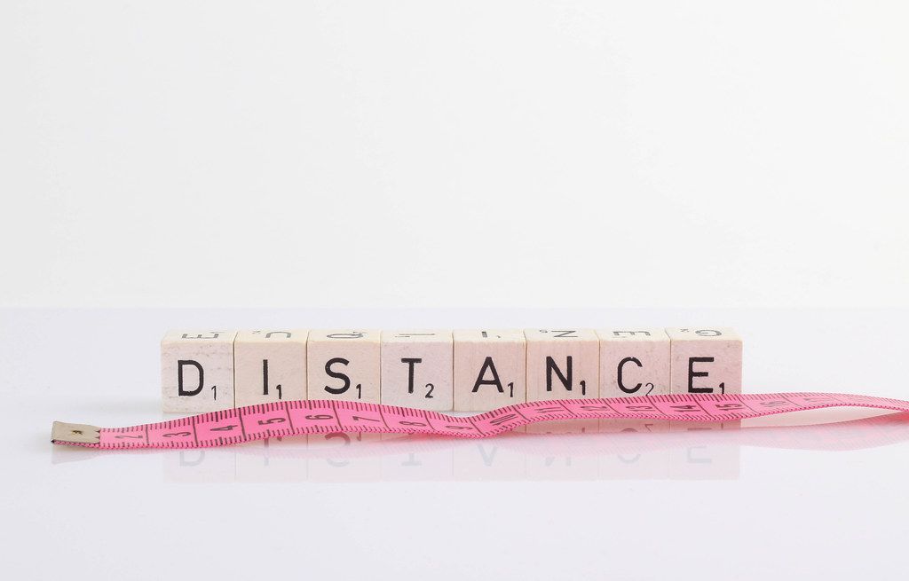 Distance text on wooden blocks with pink tape measure on white background